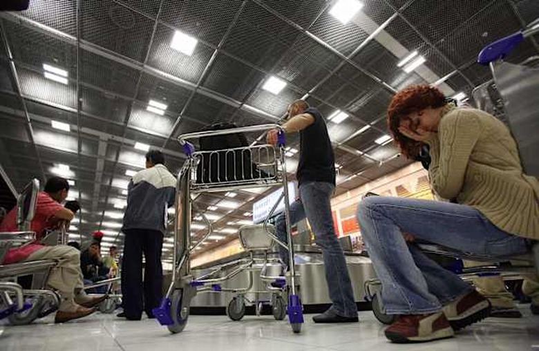 Bangkok, THAILAND: A passenger (R), arrived from the first flight, holds her head in frustration after extra ordinary delay in baggage arrivals during the opening day of Bangkok's new Suvarnabhumi airport, 28 September 2006. Passengers at Bangkok's new international airport faced delays in collecting their bags and checking in on the first full day of operations because of computer and mechanical glitches. AFP PHOTO / Saeed KHAN (Photo credit should read SAEED KHAN/AFP/Getty Images)