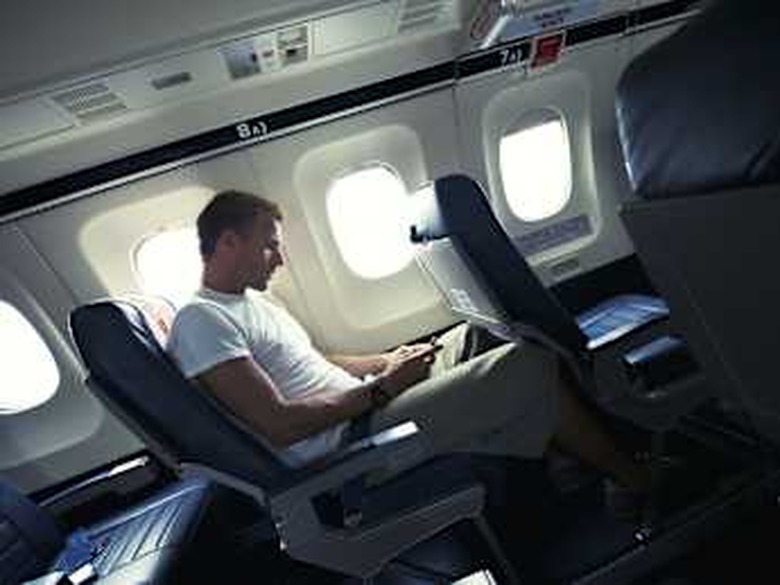 Man sits with his smartphone in the cabin of a small airplane, texting during takeoff