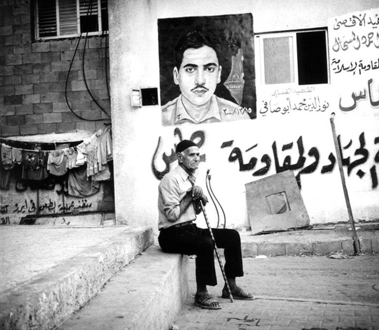 A Palestinian refugee rests his legs beneath a 'Martyr's Portrait' in Gaza City
