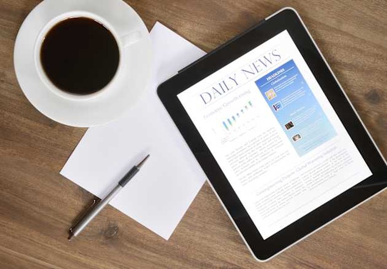 'Desktop with a Tablet PC, which shows the latest news on screen. Fresh Coffee and a Paper to take notes. Nikon D800e. Converted