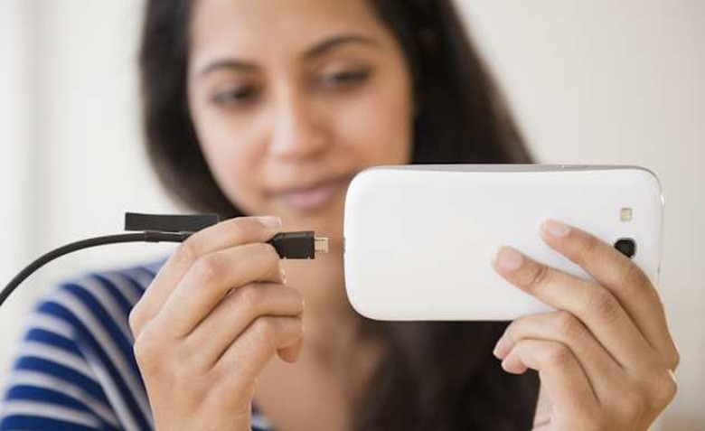 Close up of Asian woman connecting cell phone to battery