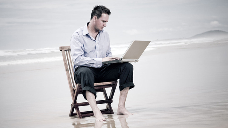A concerned man checking his laptop on the beach