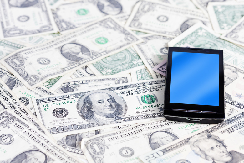 A pile of US currency, topped with a mobile phone, reminds us that money talks and can be very persuasive!