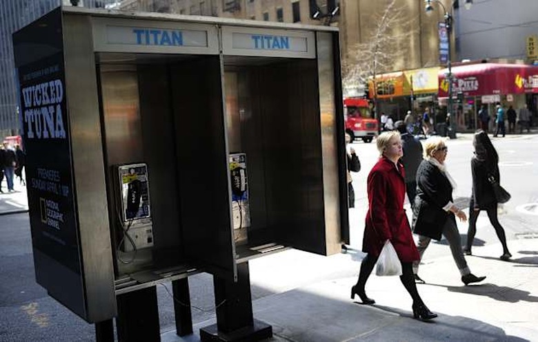 People walk by empty public pay phone bo
