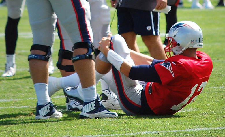 Tom Brady grabs his knee after an apparent injury