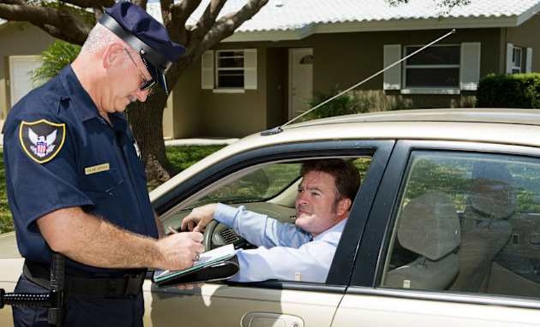 B7KYX5 Police officer writing a traffic citation while an unfortunate driver looks on from his car.Model release - YESPropert