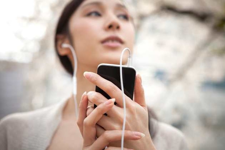 woman listening to music outside by smart phone