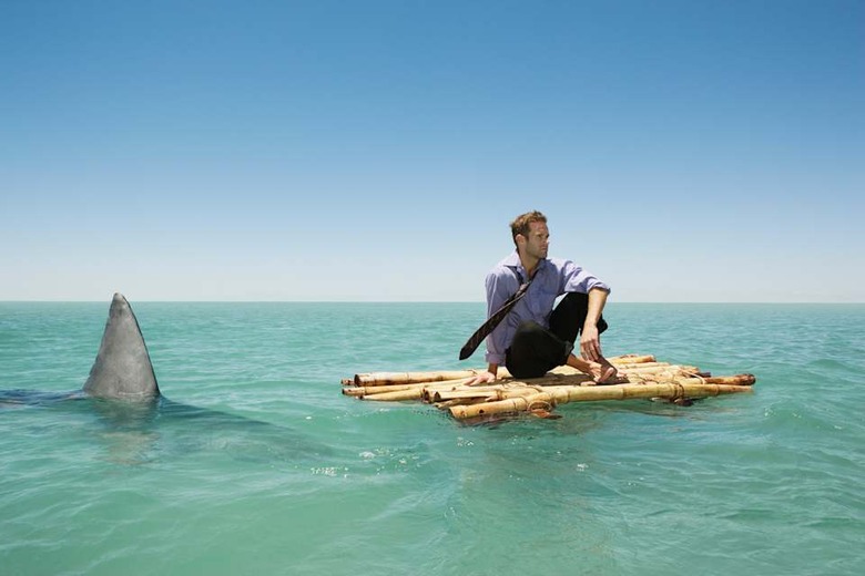 Great white shark swimming by man on raft wearing shirt and tie