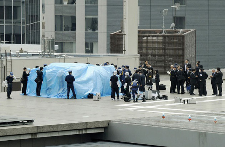 Officers cover up the drone on the Japanese Prime Minister's office
