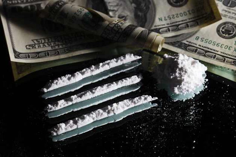 Cocaine drugs heap still life on a mirror with rolled 100 dollar bank note, close up view