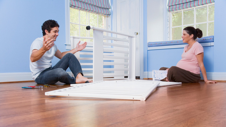 An expecting couple builds a crib for their baby