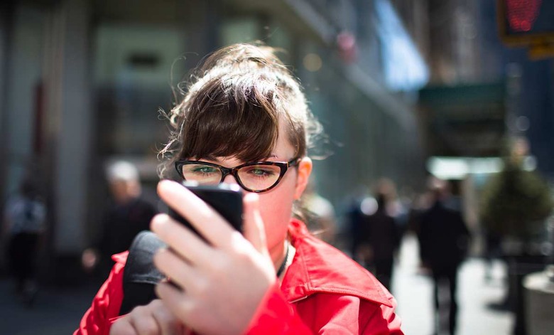 Woman on city street looking at smartphone