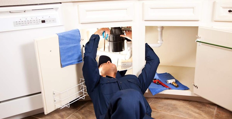 Plumber working under sink in kitchen