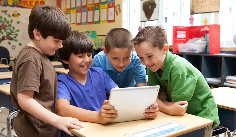 Kids looking at ipad / tablet in classroom