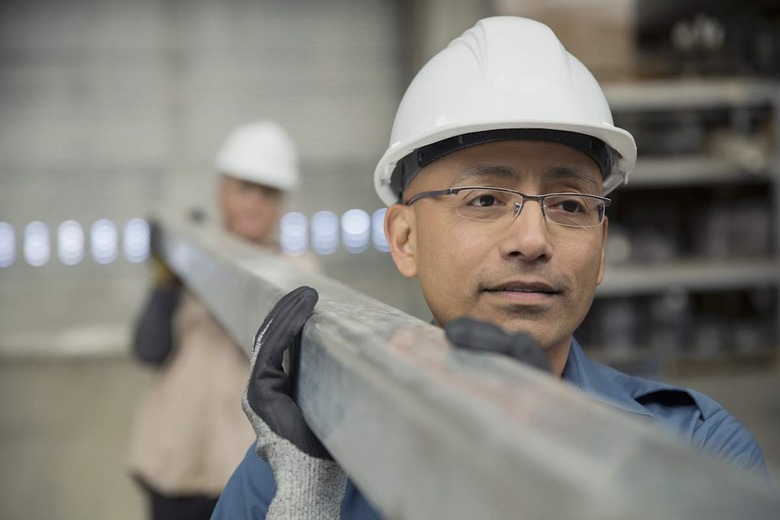Workers carrying steel beam in manufacturing plant