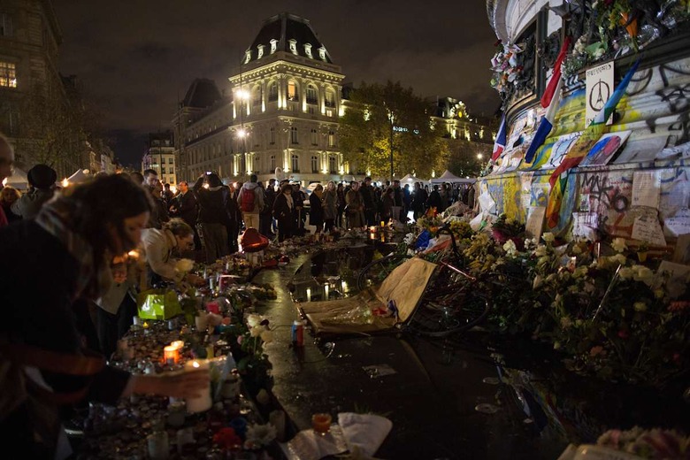 People light candles at a makeshift memorial in front of 