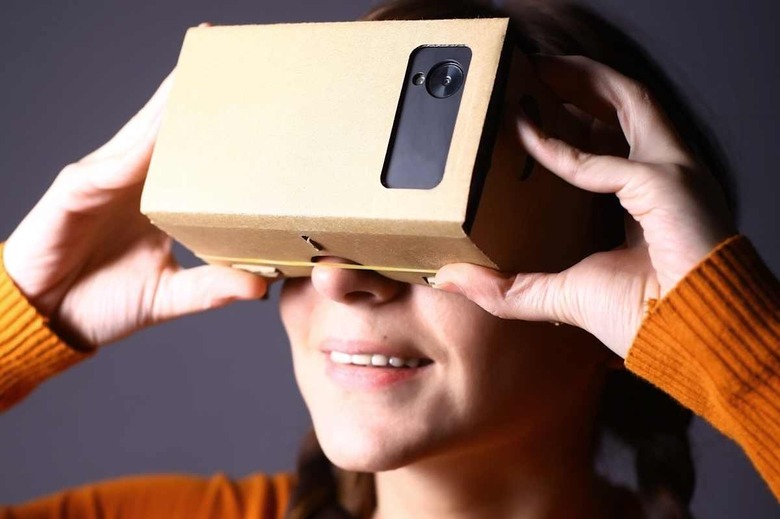 Color shot of a young woman looking through a cardboard, a device with which one can experience virtual reality on a mobile phon