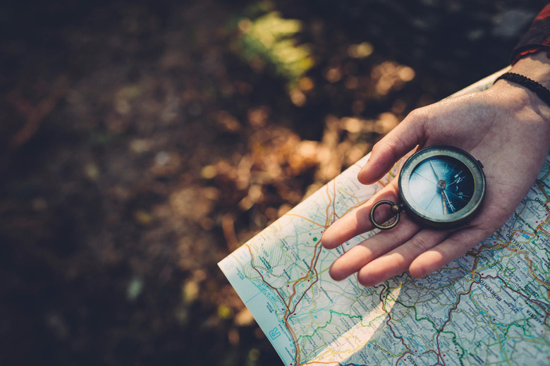 Hand holding a compass over a map 