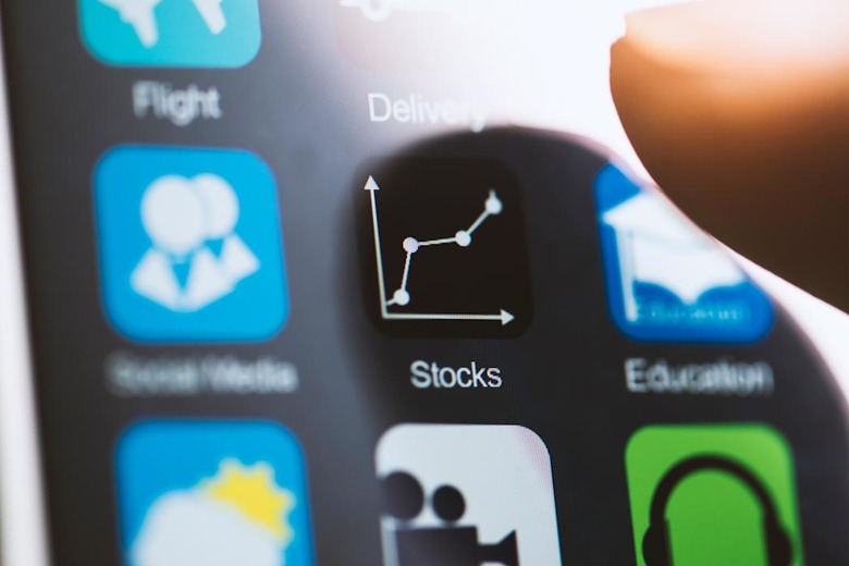 Hand touching stocks app on screen