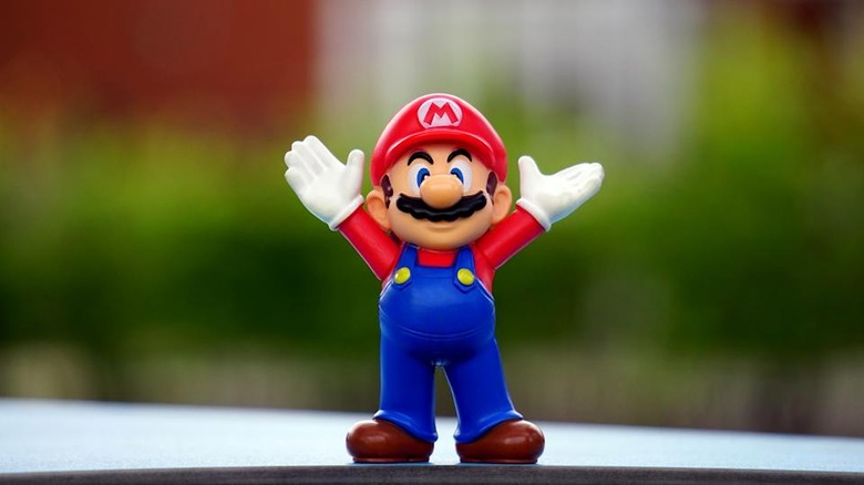 Mario stands on a windowsill with his white gloves raised in celebration