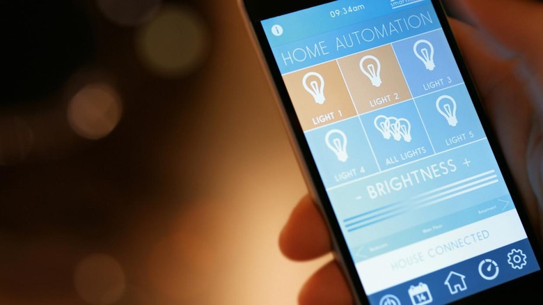 smart house, home automation, device with app icons. Man uses his smartphone with smarthome light controll app to turn on the lights of his house.