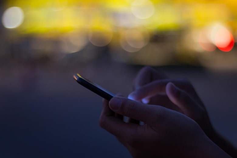 close-up hand use phone on night time in the city