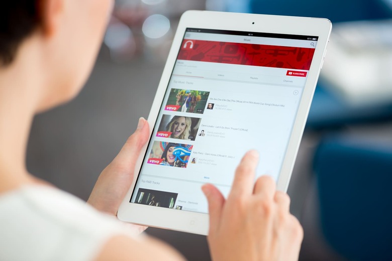 Kiev, Ukraine - May 21, 2014: Woman holding a brand new Apple iPad Air and looking on YouTube music playlist on a screen. YouTu