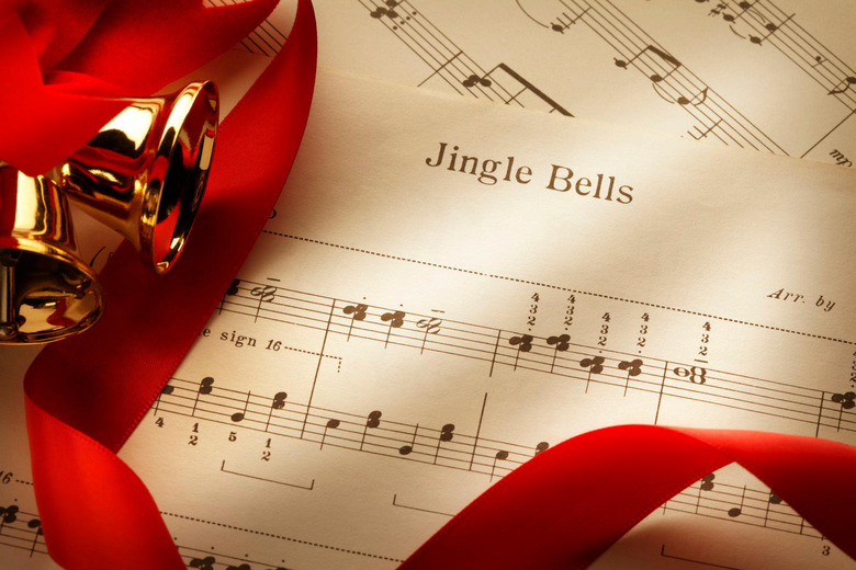 Several Christmas bells and red ribbon on the sheet music from the Christmas classic, Jingle Bells.