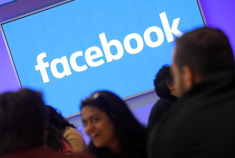 People stand in front of a logo at Facebook's headquarters in London, Britain, December 4, 2017. REUTERS/Toby Melville