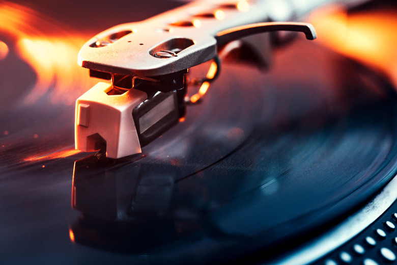 A close up shot of a running record player spinning out some music, dramatically lit with orange light. Horizontal with copy space.