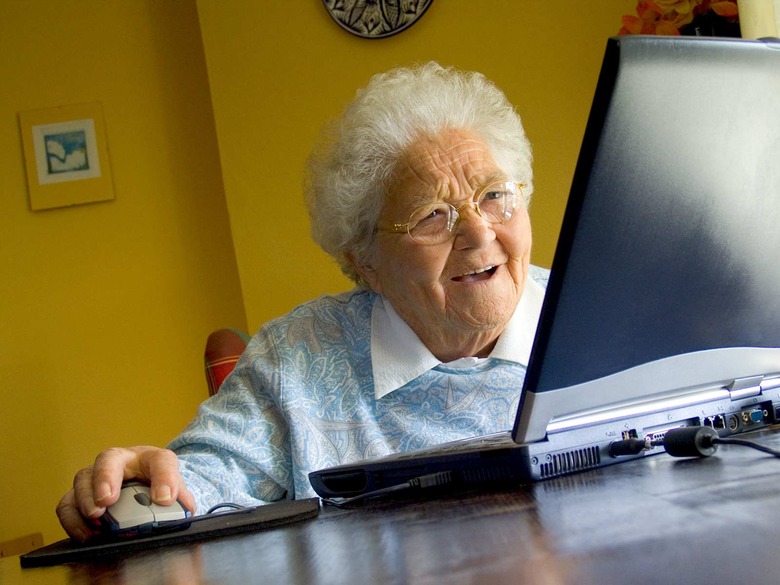 Senior elderly lady at home using her new laptop computer and its technology