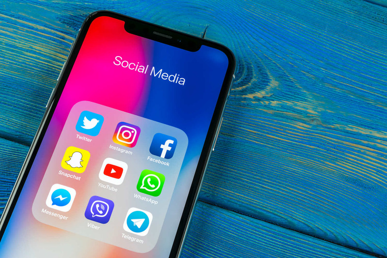Apple iPhone X on office desk with icons of social media facebook, instagram, twitter, snapchat application on screen. Social network. Starting social media app.
