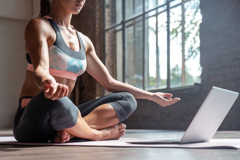 Closeup young sporty fit slim woman coach do practice video online training hatha yoga instructor modern laptop meditate Sukhasana posture relax breathe easy seat pose gym healthy lifestyle concept