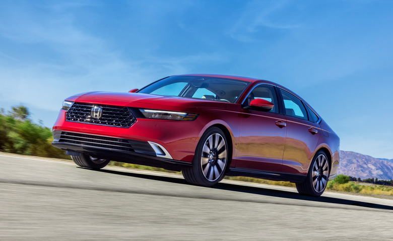 A red Honda Accord driving on flat road under blue skies with hills in the distance