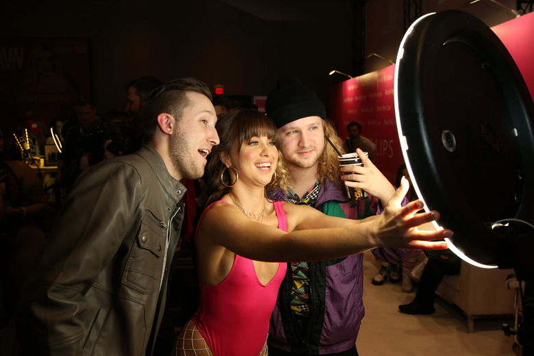 LAS VEGAS, NEVADA - JANUARY 22: Adult film actress Riley Reid (C) takes a selfie with Harrison Hays (L) and Chasen Hallford (R) of Texas in the Reid My Lips booth during the 2020 AVN Adult Expo at the Hard Rock Hotel & Casino on January 22, 2020 in Las Vegas, Nevada. (Photo by Gabe Ginsberg/WireImage)