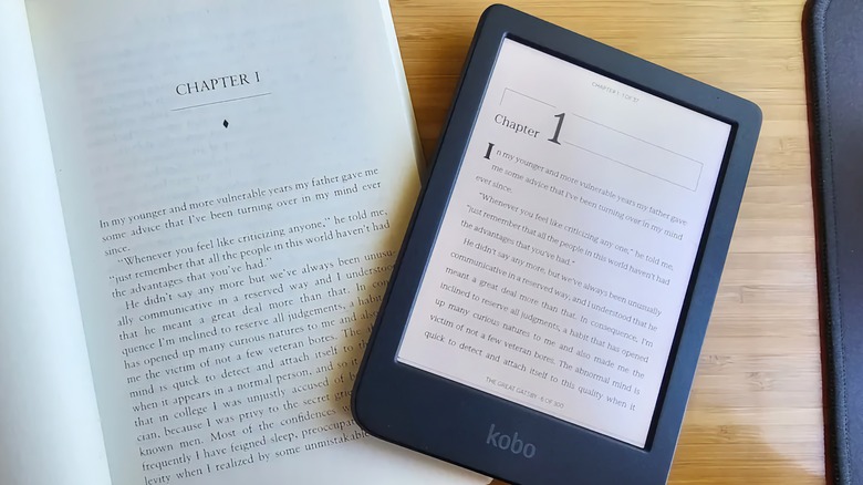 A black Kobo Libra Colour sitting on top of an open paperback book.