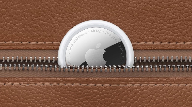 Close-up photo of an AirTag peeking out of a zippered pocket in a brown leather accessory. 