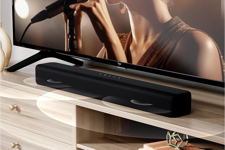 A soundbar on top of a console with a TV in the background.