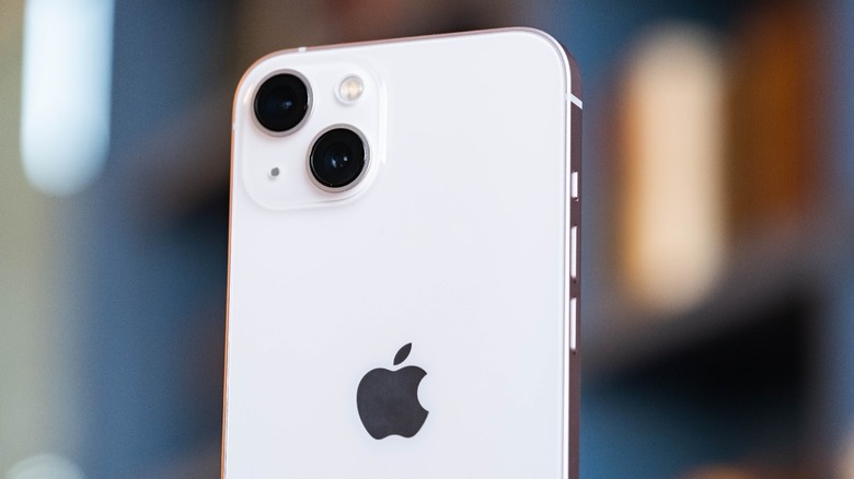 A pink iPhone 13 slightly off angle, with its rear facing the camera.