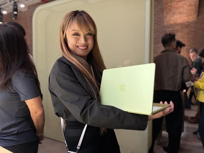 A woman cradling the yellow MacBook Neo.