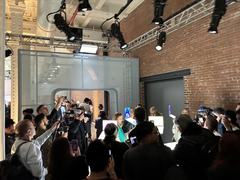 A crowd of people around some MacBook Neos on display at the Apple event.