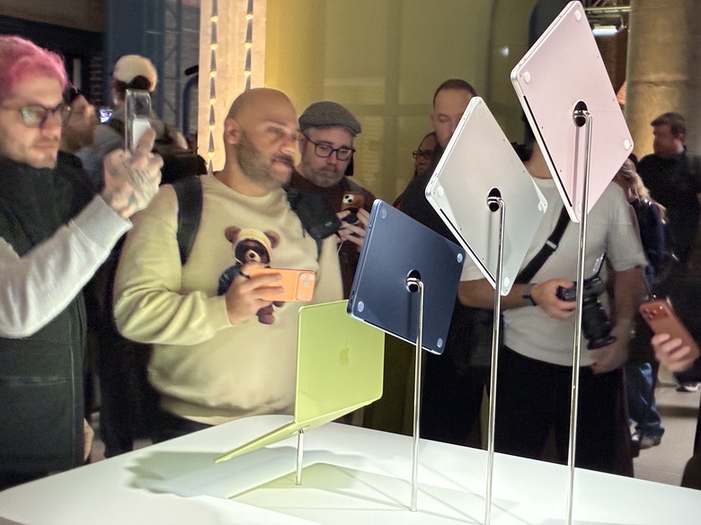 Four MacBook Neos on stands at an event