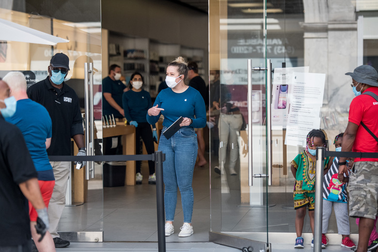 CHARLESTON, SC - MAY 13: An employee at the Apple Store helps a customer on May 13, 2020 in Charleston, South Carolina. Customers had their temperatures taken and were required to wear masks at the South Carolina store, as locations in Idaho, Alabama, and Alaska reopened as well following forced closures due to the coronavirus. (Photo by Sean Rayford/Getty Images)