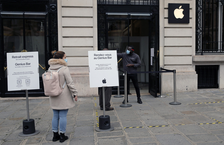 PARIS, FRANCE - OCTOBER 30: A woman wearing a protective face mask queues in front of an Apple store that remained open on the first day of the second national lockdown as part of the COVID-19 measures to fight a second wave of the coronavirus disease (COVID-19) on October 30, 2020 in Paris, France. France has imposed another national lockdown for a minimum of four weeks as the number of coronavirus cases soars during the second wave. Businesses which were defined in the spring as non-essential, including bars, restaurants, museums will be closed. (Photo by Chesnot/Getty Images)