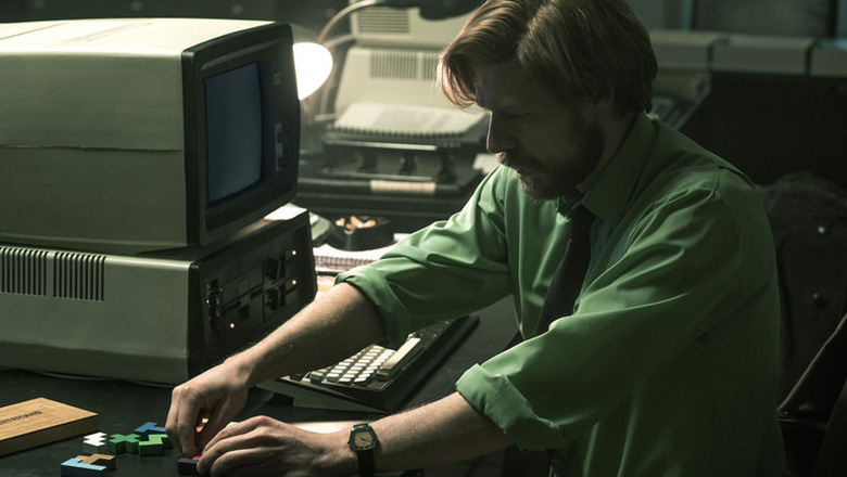 Alexey Pajitnov (Nikita Efremov) moves some Tetris-style blocks around in a desk next to an old computer in the movie 'Tetris.'
