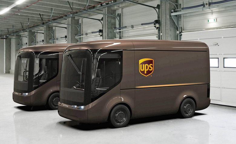 Two UPS concept delivery vans from auto maker Arrival are parked in the empty end of a warehouse / loading dock facility.