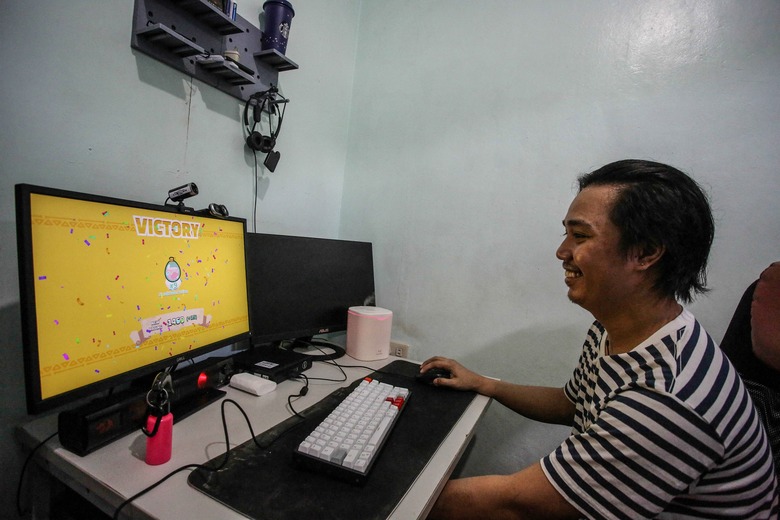 This photo taken on December 13, 2021 show Dominic Lumabi playing Axie Infinity on his computer, an NFT game where he earns cryptocurrency to support his family during the pandemic, in Marikina, suburban Manila. - Axie Infinity is a blockchain-based play-to-earn game that exploded in popularity in developing nations such as the Philippines as Covid-19 has destroyed jobs and forced many to stay home. - TO GO WITH Philippines-Vietnam-tech-crypto-gaming,FOCUS by Allison Jackson and Alice Philipson (Photo by Jam STA ROSA / AFP) / TO GO WITH Philippines-Vietnam-tech-crypto-gaming,FOCUS by Allison Jackson and Alice Philipson (Photo by JAM STA ROSA/AFP via Getty Images)