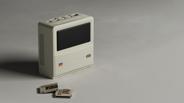 Ayaneo's AM01 mini PC with two game cartridges sitting in front. The mini PC looks like Apple's original Macintosh.
