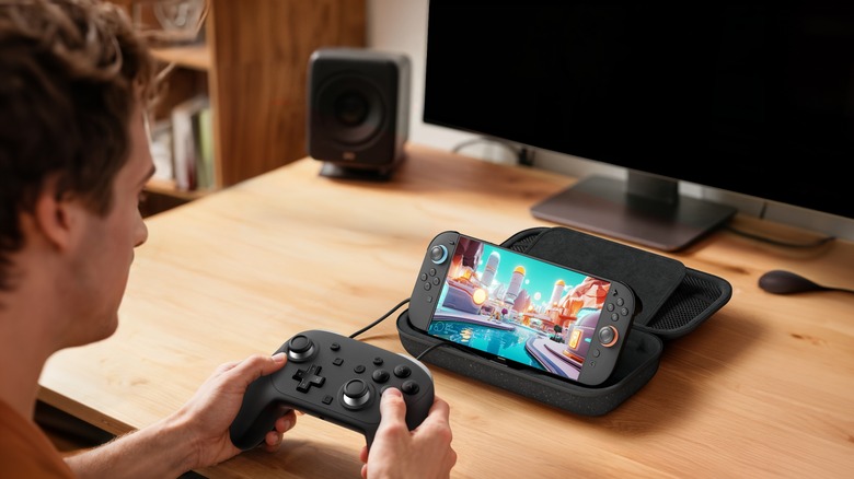 A person playing a Switch 2 that's propped up and charging in a Belkin Charging Case.