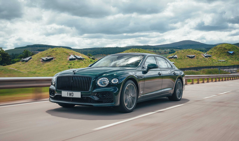 The Bentley Flying Spur plug-in hybrid drives down a highway with hills in the background.